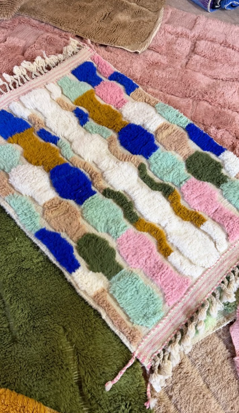 Stack of folded Moroccan rugs in warm tones